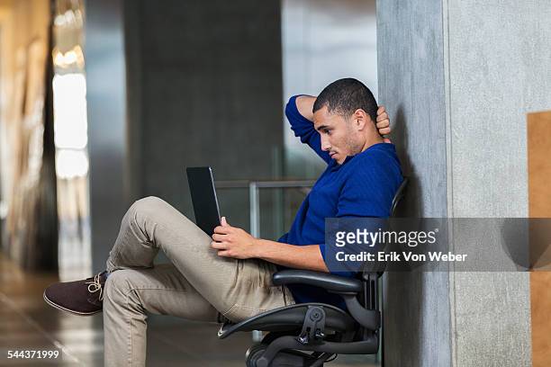 man working on laptop in creative office - pernas cruzadas imagens e fotografias de stock