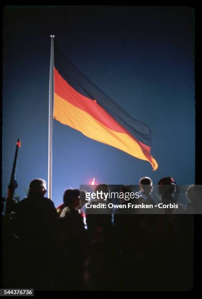 Lights shine upon a German flag at festivities celebrating the reunification of East and West Germany into the single country of Germany. Berlin,...