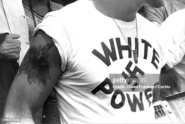 Man wears a pendant made out of a bullet and a t-shirt that reads "White Power" around a swastika at a gathering of American Nazis. Protected by anti...