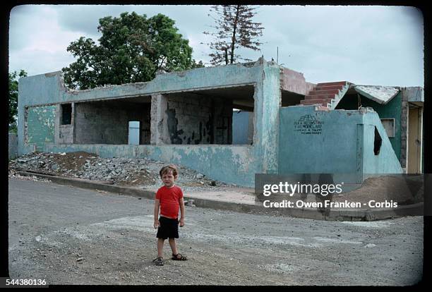 Young boy stands in front of a building destroyed in a 1970 earthquake, Managua, Nicaragua.