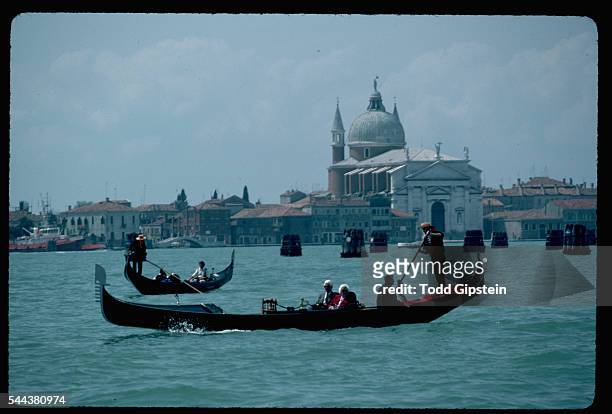 Couple enjoys a gondola ride along the Grand Canal, with a view of San Giorgio Maggiore church in the background.