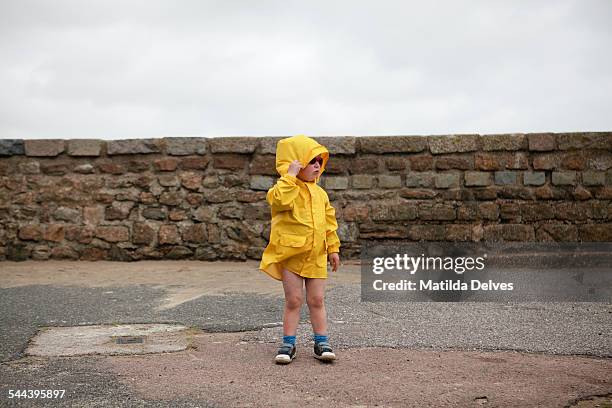 young boy wearing a yellow jacket at the beach - oil skin stock pictures, royalty-free photos & images