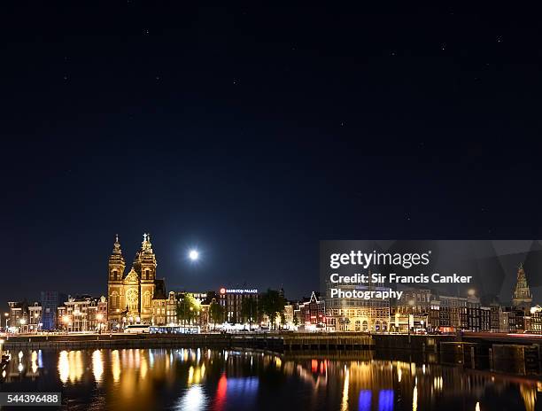 amsterdam skyline illuminated at night with full moon and reflection on amstel river, the netherlands - skyline amsterdam stock pictures, royalty-free photos & images