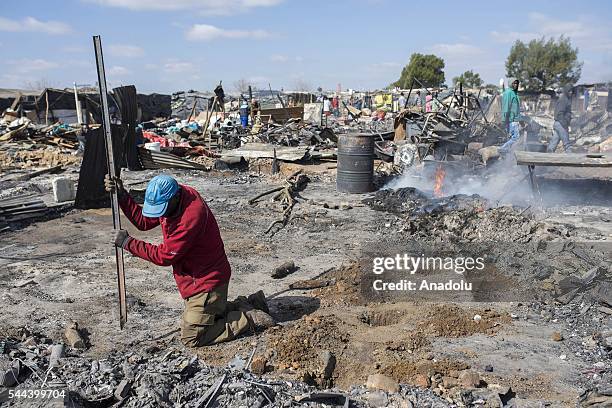 Residents of the Plastic View informal settlement collects usable household goods after a huge fire destroyed over 200 homes in the slum area, east...