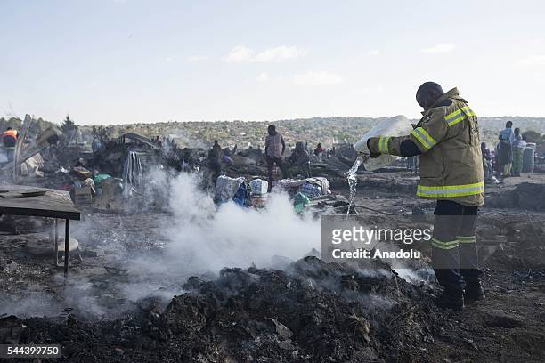 Firefighters cools down the area after a huge fire destroyed over 200 homes in the slum area, east of the South African city Pretoria on July 03,...
