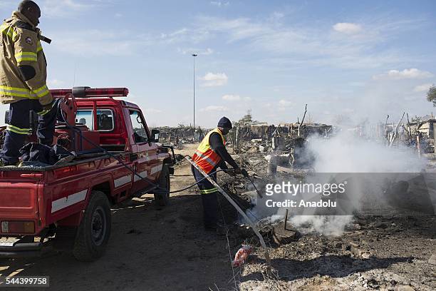 Firefighters cools down the area after a huge fire destroyed over 200 homes in the slum area, east of the South African city Pretoria on July 03,...