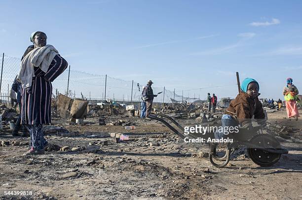 Residents of the Plastic View informal settlement collects usable household goods after a huge fire destroyed over 200 homes in the slum area, east...