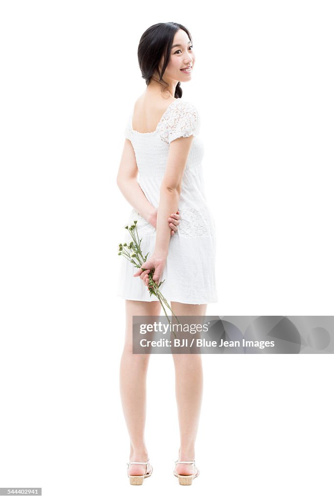 Young woman holding a bunch of flowers behind her back