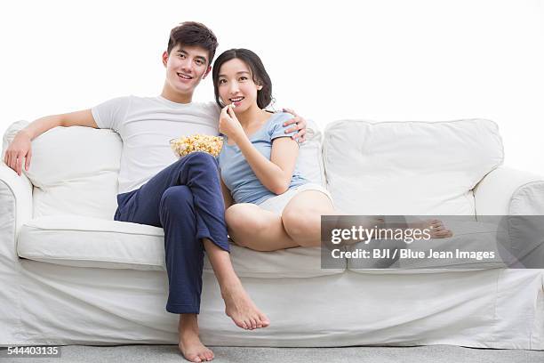 young couple watching movie in living room - asian man barefoot foto e immagini stock