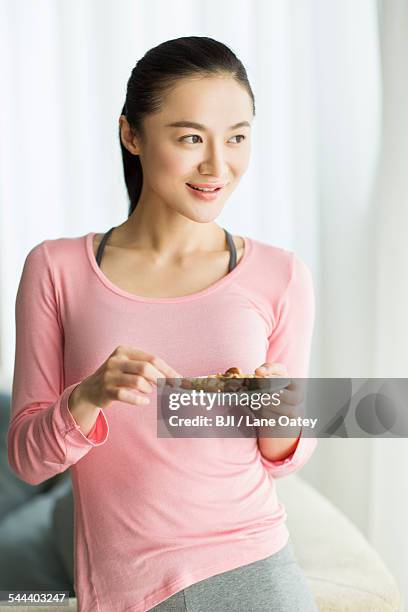 happy young woman eating nuts - almond joy stock pictures, royalty-free photos & images