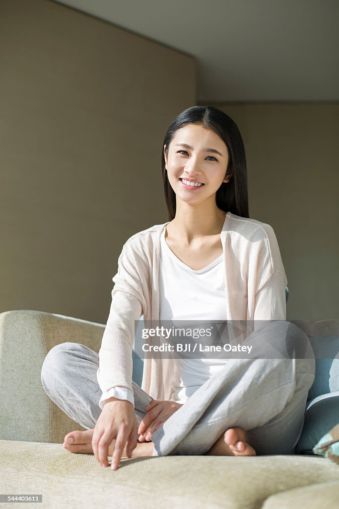 Happy young woman sitting on sofa