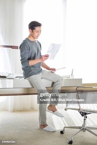 fashion designer looking at sketch - asian man sitting casual imagens e fotografias de stock