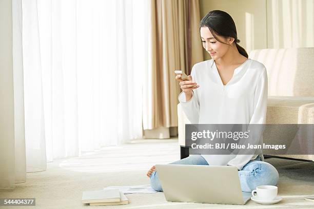 young woman using smart phone and laptop at home - sitting on ground stock pictures, royalty-free photos & images
