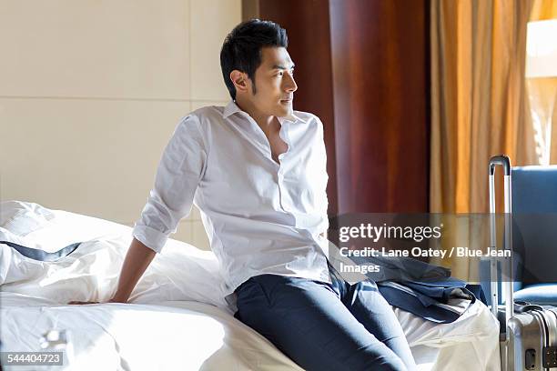 young businessman resting in hotel room - asian man suite stock-fotos und bilder