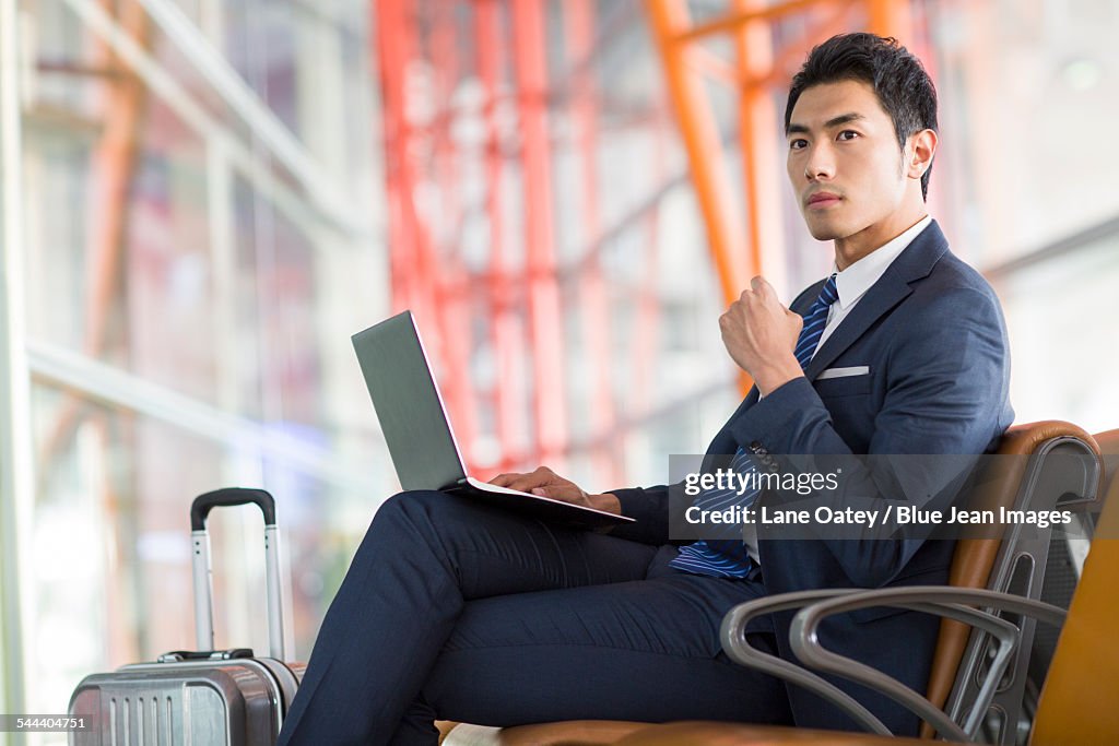 Young businessman using laptop in airport