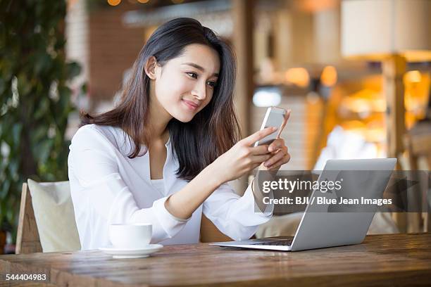 young woman using smart phone in cafe - eastern ストックフォトと画像