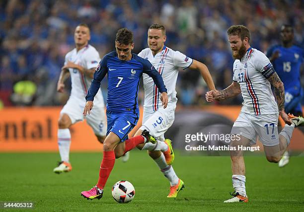 Antoine Griezmann of France and Aron Gunnarsson of Iceland compete for the ball during the UEFA EURO 2016 quarter final match between France and...
