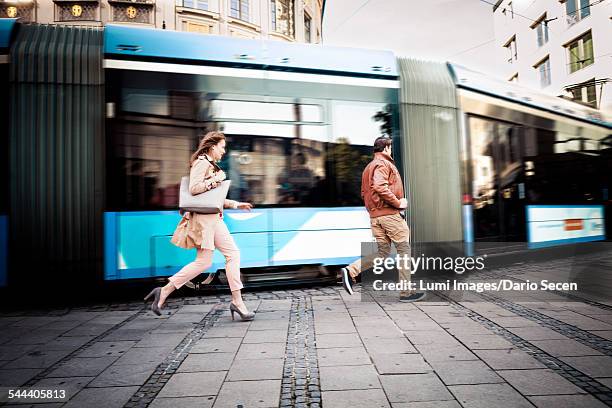 young couple running after cable car, munich, bavaria, germany - bus road stock-fotos und bilder