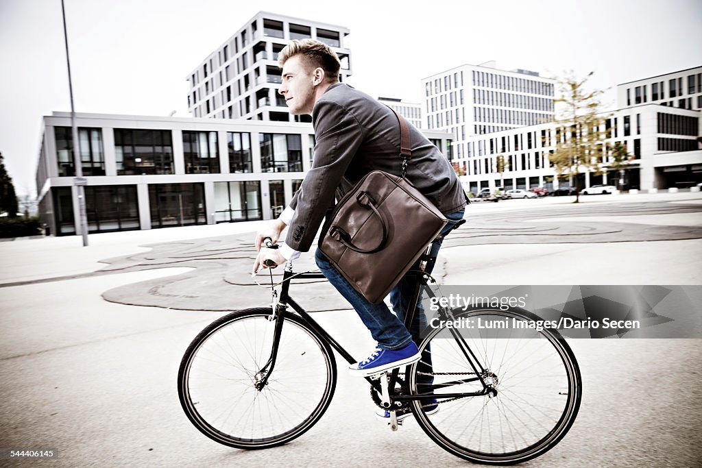 Young businessman riding bicycle, Munich, Bavaria, Germany