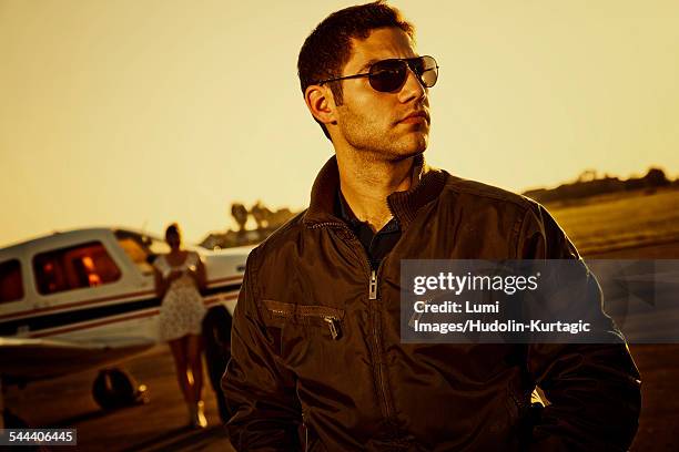 young couple standing in front of propeller airplane - male bomber jacket stock pictures, royalty-free photos & images