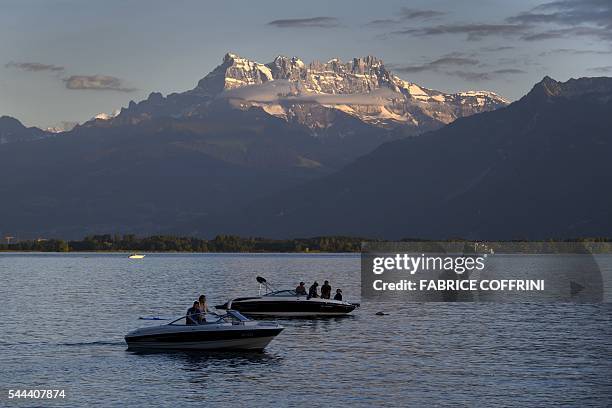 Boats are seen on the Lake Geneva with the "Dents du Midi" multi-summited mountain as background on July 3, 2016 in Montreux. / AFP / FABRICE COFFRINI