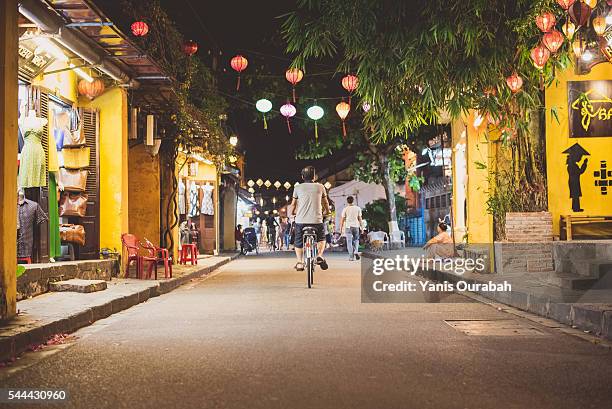 cyclist male in hoi an traditional street by night in summer with lanterns - hoi an stockfoto's en -beelden