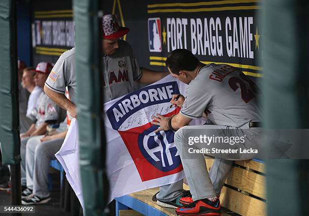 Teammates Jose Fernandez and Cole Gillespie of the Miami Marlins sign a flag for soldiers before their game against the Atlanta Braves at Fort Bragg...