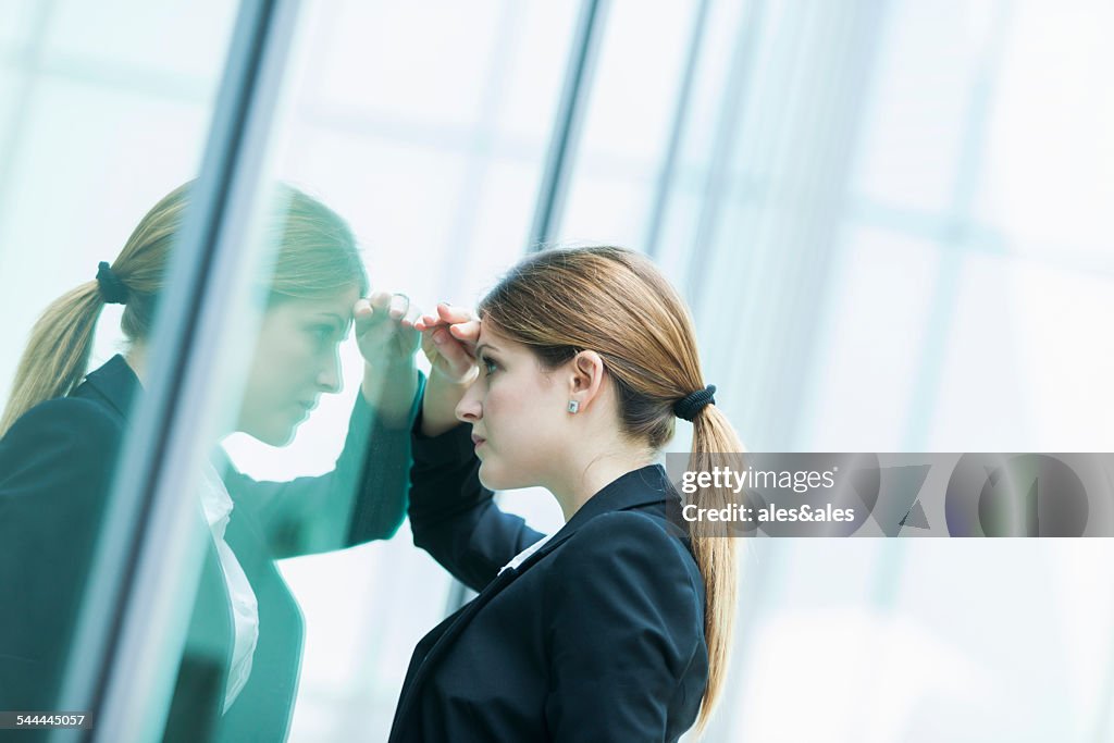 Businesswoman peering through glass window
