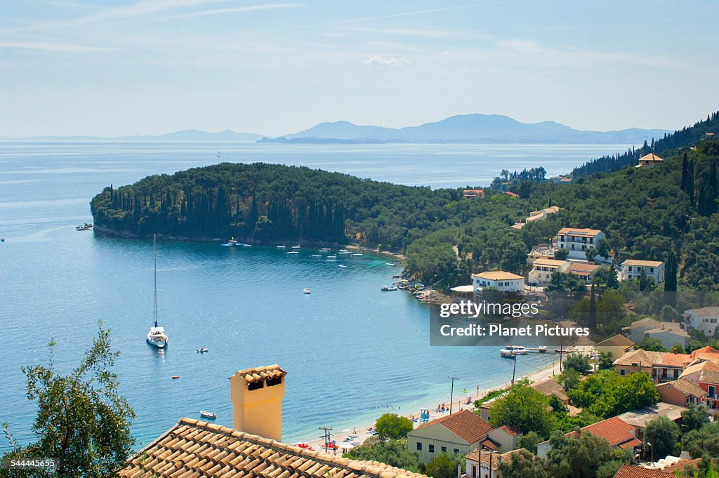 View of coastal village rooftops and bay, Corfu, Greece
