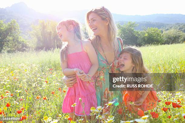 mid adult woman and two daughters laughing in wildflower meadow, majorca, spain - poppies stock pictures, royalty-free photos & images