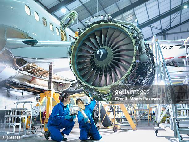 aircraft engineers inspecting jet engine in aircraft maintenance factory - hangar stockfoto's en -beelden