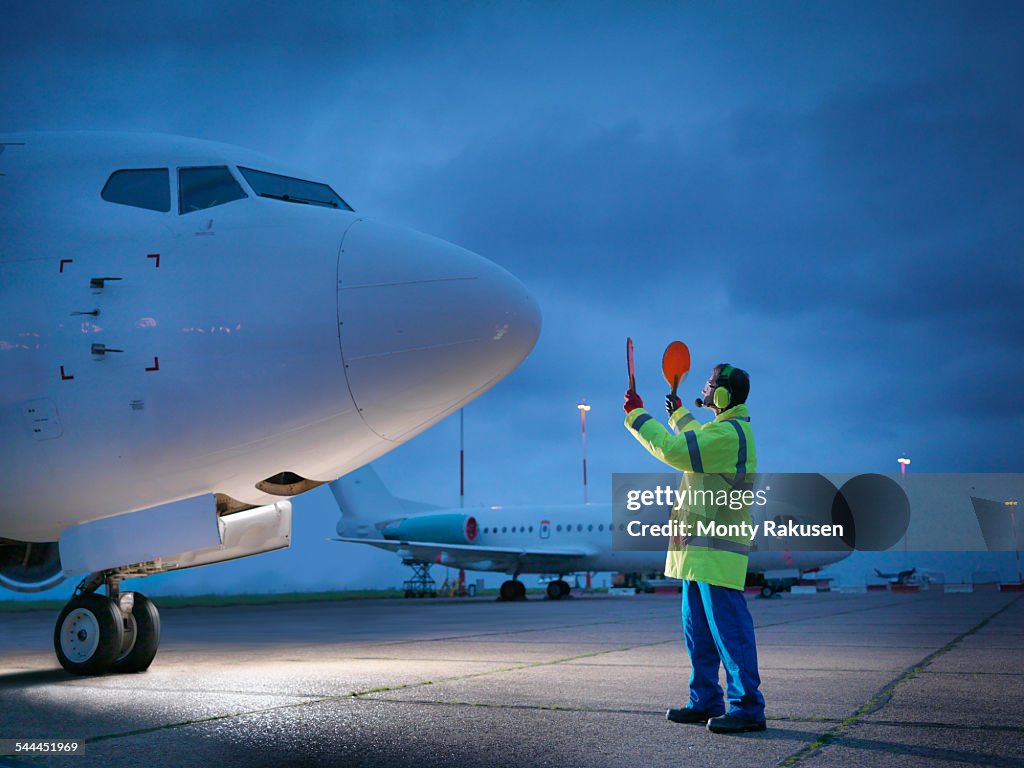 Airport Worker Guiding Aircraft On Runway At Night High-Res Stock Photo ...