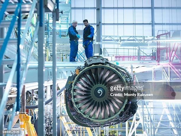 aircraft engineers standing on wing with jet engine in aircraft maintenance factory - luftfahrzeug stock-fotos und bilder