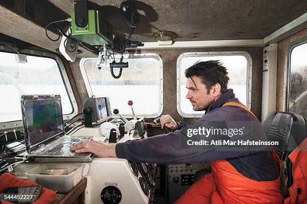 fisherman driving fishing boat using laptop - olafsvik stock pictures, royalty-free photos & images