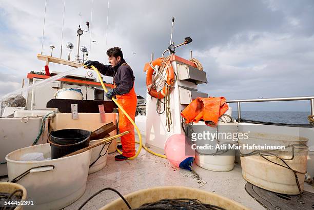 fisherman hosing down fishing boat - olafsvik stock pictures, royalty-free photos & images