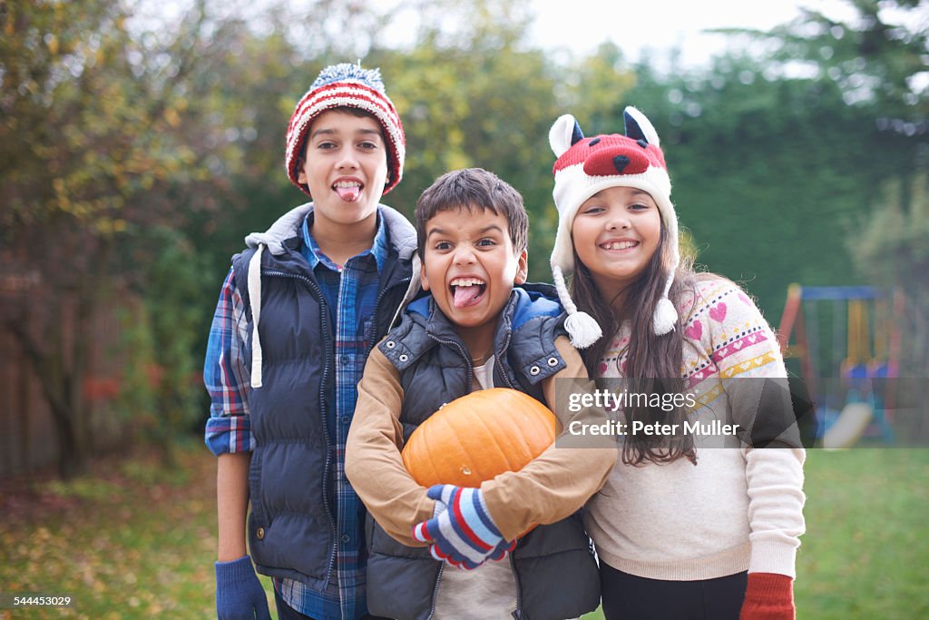 Siblings with pumpkin posing in garden