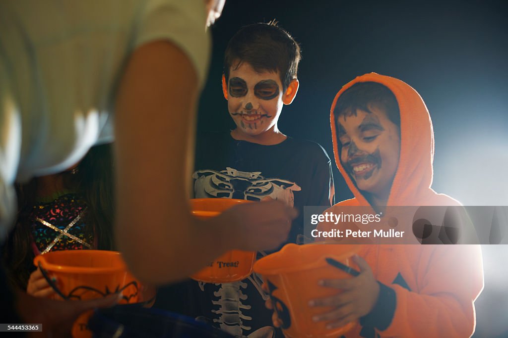 Three children wearing halloween costumes trick or treating