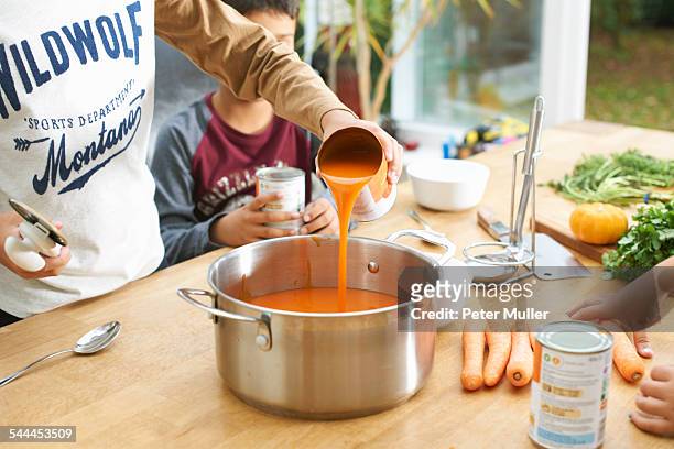 cropped shot of boy pouring tin of tomato soup into saucepan - soup stock pictures, royalty-free photos & images