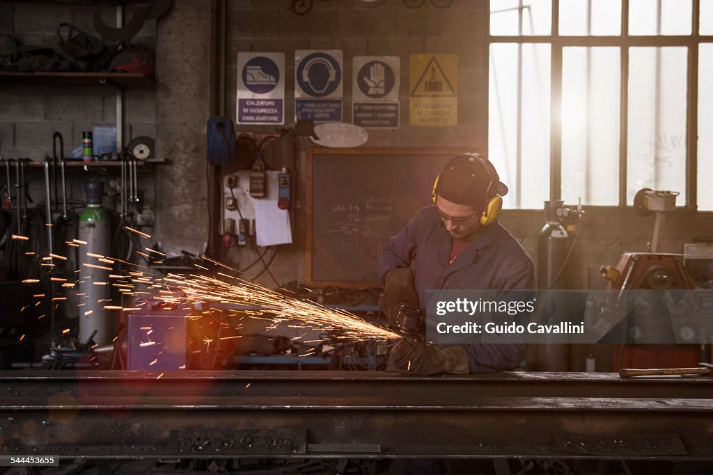 Welder cutting iron in workshop
