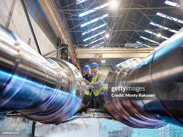 engineers inspecting finished steel rollers in engineering factory, low angle view - factory wide angle stock pictures, royalty-free photos & images