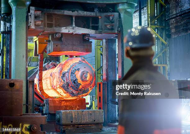 steelworker inspects hot steel in forging press in steelworks - sheffield steel stock pictures, royalty-free photos & images