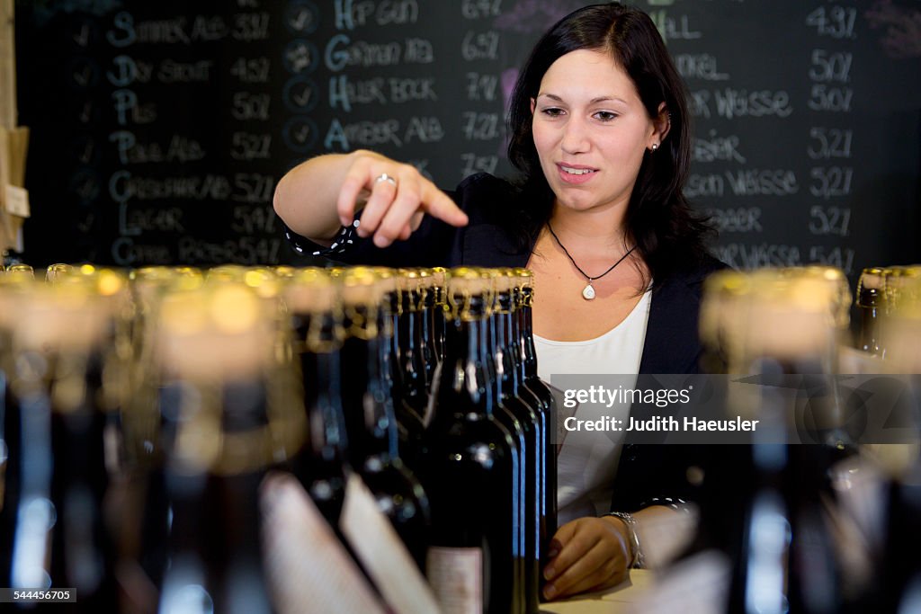 Woman counting bottles of wine in shop