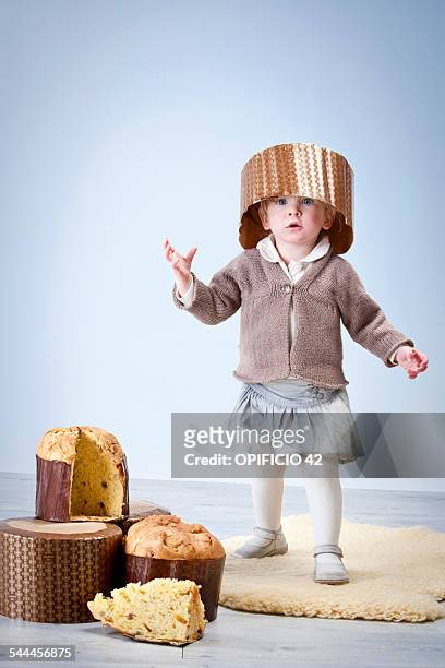 portrait of female toddler wearing pannetone cake case as hat - cake case stock pictures, royalty-free photos & images