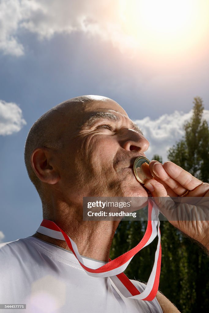 Sportsman kissing medal
