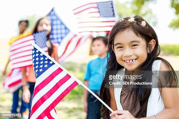 niedlich kleines mädchen bietet amerikanische flagge - patriotic flags stock-fotos und bilder
