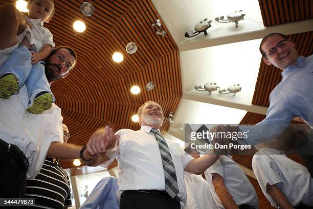 Low-angle view of men, one with an infant on his shoulder, as they dance during an Orthodox Jewish wedding, Jerusalem, Israel, August 29, 2014. The...