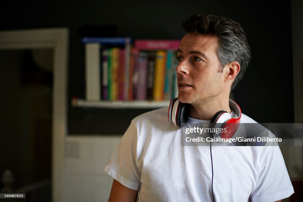 Man at home with red headphones over his neck looking away