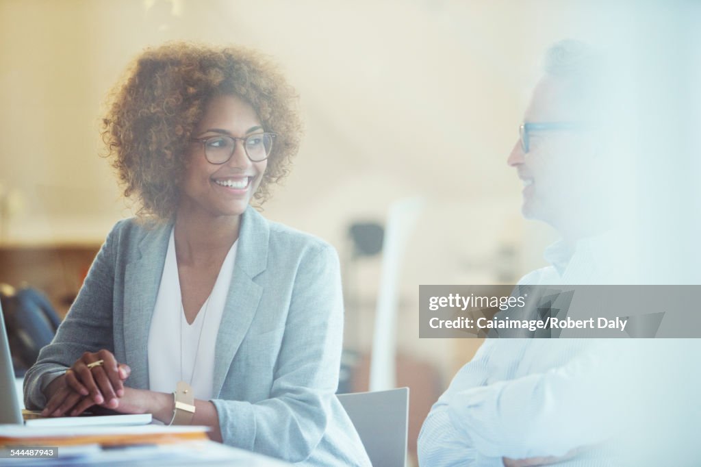 Two office workers talking at desk