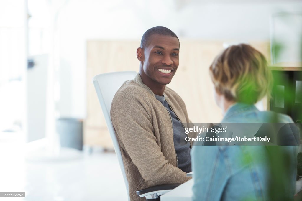 Man and woman sitting in office,smiling and talking