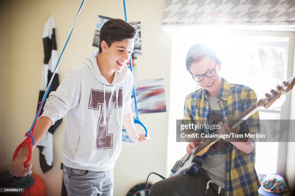 Two teenage boys having fun and playing electric guitar in room